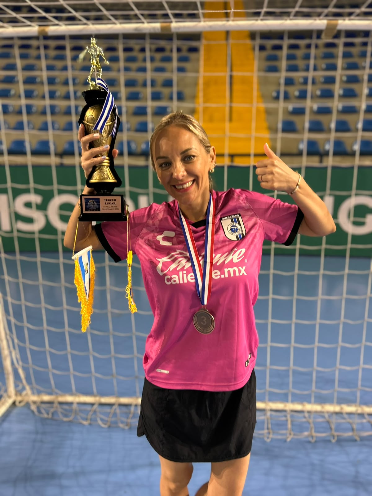 Entrenadora de Gallos Smiling con el trofeo de tercer lugar del Guatemala Futsal Down